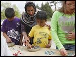  Amaan Omer, 10, works on crafting his own garden stone as his mother, Fareena Omer, center, helps his brother Ayman, 6, create another at Olander Park in Sylvania.