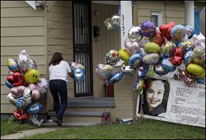 Culema Nevarez adds balloons to a growing tribute outside the home of Gina DeJesus in Cleveland.