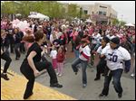  Members of the Toledo Reign football team, in white and purple shirts, exercise with survivors and supporters prior to the start of the Making Strides Against Breast Cancer for the American Cancer Society walk at Levis Commons in Perrysburg.