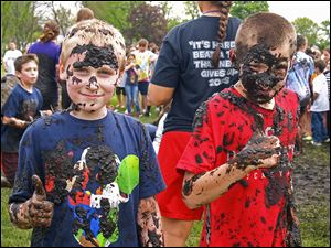 Brandon Adams, left, and Kenneth Poupard got muddy during the “Pan­ther Prowl Mud Run,” a walk-a-thon of sorts held by Wayne Trail Ele­men­tary. Prin­ci­pal Lonny Riv­era said the intent was to boost interest in the annual fund-raiser.