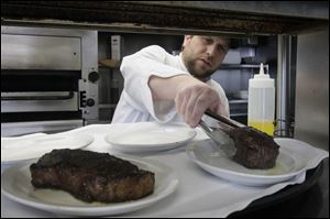 Chef Tim Childers places a 10-ounce filet mignon onto a plate a plate next to a 14-ounce New York strip at Rockwell's.