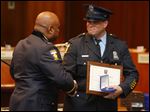  Toledo Police Chief Derrick Diggs, left, presents a Meritorious Service Medal to Officer Mark Johnson during the Toledo Police Department Awards Ceremony at One Government Center today.