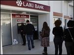  People queue to use an ATM machine outside of a Laiki Bank branch in Larnaca, Cyprus, Saturday, March 16, 2013. Many rushed to cooperative banks which are open Saturdays in Cyprus after learning that the terms of a bailout deal that the cash-strapped country hammered out with international lenders includes a one-time levy on bank deposits. The move, decided in an extraordinary meeting of the finance ministers of the 17-nation eurozone in the early hours Saturday, is a major departure from established policies. Analysts have warned that making depositors take a hit threatens to undermine investors' confidence in other weaker eurozone economies and might possibly lead to bank runs. (AP Photo/Petros Karadjias)