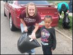  Lourdes student Amanda Borton helped with the cleanup of streets near a Toledo family emergency shelter, and she is with Toledo resident Calvina Giles, 5.
