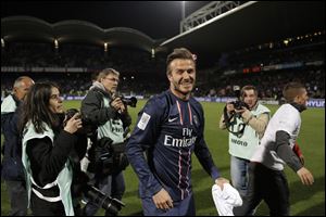 Paris Saint Germain's David Beckham celebrates their title after winning their French League One soccer match against Lyon, in Lyon, central France, Sunday.