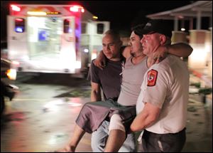 Johnny Ortiz, left, and James South, right, carry Miguel Morales, center, who was injured in a tornado, to an ambulance in Granbury, Texas, Wednesday.