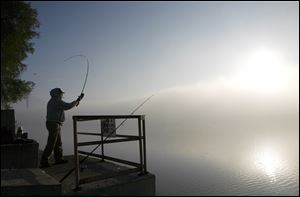 Terry Van Bibber, Toledo, casts his line out into the Maumee River as fog envelops the area.