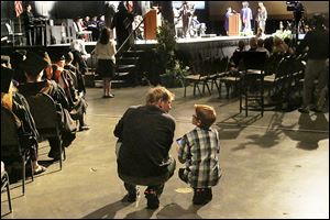 Brian Pietrzak of Sylvania has a word with his son, Rickie, 10, right, as they wait for Rickie's mother, Melissa, to accept her diploma in nursing.