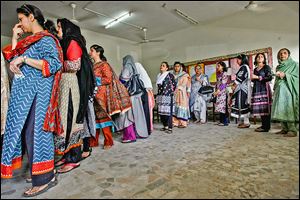 Pakistani women line up to cast ballots during a repolling for the general elections in a Karachi district. The shooting death of a party co-founder kept many home.