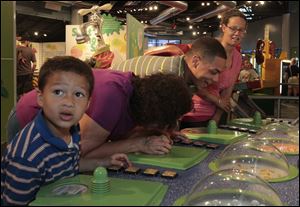Jorge Aguilar, 6, left, his grandmother Nedra Pike, and parents Ryan Pike and Whitney Mekus react to Sniff Sniff U Stink, an interactive exhibit at Grossology. Each member of the Defiance family took a whiff of something from the human body at the Imagination Station in downtown Toledo on Sunday. 