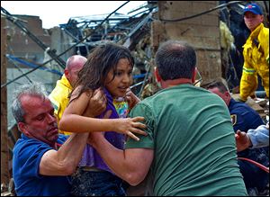 A child is pulled from the rubble of the Plaza Towers Elementary School in Moore, Okla., and passed along to rescuers.