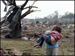  A woman carries a child through a field near the collapsed Plaza Towers Elementary School in Moore, Okla., Monday, May 20, 2013. The relationship between the woman and the child was not immediately known. A tornado as much as half a mile (.8 kilometers) wide with winds up to 200 mph (320 kph) roared through the Oklahoma City suburbs Monday, flattening entire neighborhoods, setting buildings on fire and landing a direct blow on an elementary school. (AP Photo Sue Ogrocki)