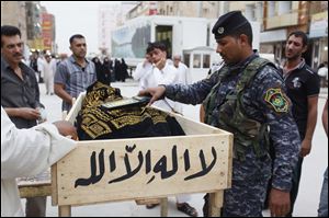 An Iraqi policeman runs his metal detector over the body of Mohammed Adnan, 22, at a checkpoint as the body arrives for burial in the holy Shiite city of Najaf, 160 kilometers (100 miles) south of Baghdad, Iraq, Monday, May 20, 2013. A wave of car bombings across Baghdad's Shiite neighborhoods and in the southern city of Basra killed and wounded dozens of people, police said. (AP Photo/ Alaa al-Marjani)