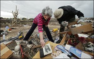 Lea Bessinger salvages a picture of Jesus as she and her son, Josh Bessinger, sort through the rubble of Ms. Bessinger's home in Moore, Okla. Some residents returned Tuesday to assess the damage.
