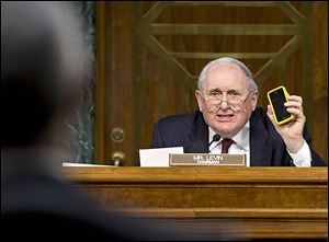 Sen. Carl Levin (D., Mich.) holds up his Apple iPhone while questioning Apple CEO Tim Cook about methods used by corporations to shift profits offshore.
