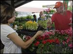  Martha Bradley of Toledo buys flowers from Andy Keil, of Andy Keil Greenhouse in Swanton, at last year's Flower Day event at the Toledo Farmers' Market. The market is at Superior and Market streets, on the south end of downtown.