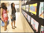  Myra Beyene, right, shows her mother, Zebib Beyene Gradina her award-winning art work during an art fair at McCord Junior High.