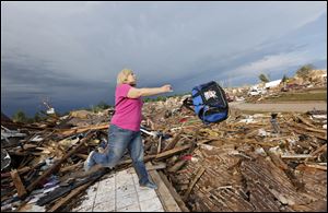 Penny Phillips throws out a bag of salvaged clothing as she goes through the remains of her home on Tuesday in Moore, Okla. that was destroyed by Monday's tornado.