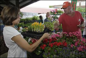 Martha Bradley of Toledo buys flowers from Andy Keil, of Andy Keil Greenhouse in Swanton, at last year's Flower Day event at the Toledo Farmers' Market. The market is at Superior and Market streets, on the south end of downtown.