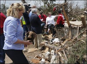 Oklahoma Gov. Mary Fallin, left, picks up a stuffed dog Monday from the rubble of Kimberly Graham's home, at the Steelman Estates Mobile Home Park, which was hard hit in Sunday's tornado, near Shawnee, Okla. Graham is seated at rear in white talking with Red Cross workers.