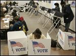  Sharon Booth uses a paper ballot, in foreground, as she votes at the Toledo-Lucas County Kent Branch Library in Toledo, Ohio.