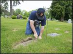  Martin Doll of Temperance cuts away the  growth over the gravestone at Toledo Memorial Park in Sylvania for Walter Pietrzak, Jr., who served in the Navy in World War ll. The Toledo-Lucas County Memorial Day Association ensures that veterans’ graves are marked with a U.S. flag on Memorial Day.