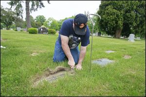 Martin Doll of Temperance cuts away the  growth over the gravestone at Toledo Memorial Park in Sylvania for Walter Pietrzak, Jr., who served in the Navy in World War ll. The Toledo-Lucas County Memorial Day Association ensures that veterans’ graves are marked with a U.S. flag on Memorial Day.