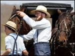  FILE - In this April 9, 2013 file photo, Freeman Burkholder, right, takes the headpiece off of his horse in Bergholz, Ohio.  Bergholder and other Amish now imprisoned in beard-cutting attacks on fellow Amish in Ohio have been granted a religious freedom exemption from a requirement to attend high-school equivalency classes behind bars.  (AP Photo/Scott R. Galvin, File)