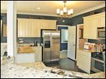  The kitchen’s antiqued white cabinets and dark walls make a perfect back-drop for the beautifully veined granite countertop.