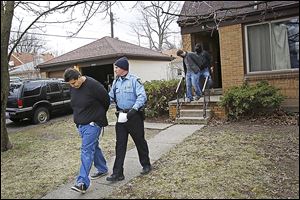 Adam Michalak, left, and Joshua Bennett, right, are led out of a South Toledo home by police after a Toledo police raid in April. 