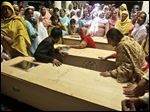  Pakistani women, mourn next to the bodies of their friends and relatives, who were killed in a gas cylinder explosion today on a minibus, in Gujrat, Pakistan.