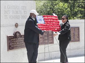 Toledo Mayor Mike Bell and City Council President Paula Hicks-Hudson place a floral flag during the city's Memorial Day ceremony that also featured bagpipes.