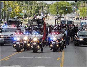 Toledo Police Department motorcycles lead the city's Memorial Day parade, which at times proved to be a loud procession of marching bands, military vehicles, clowns, and candy throwers.  