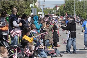 U.S. flags are distributed along the Memorial Day parade route on Jackson Avenue. A later service organized by the Toledo-Lucas County Memorial Day Association brought many somber moments.