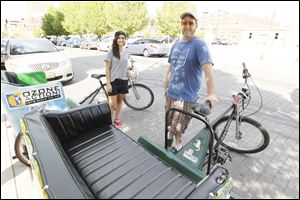 Maxwell Austin, owner of Glass City Pedicabs, right, and Brittany Ryan, left, with their bikes.