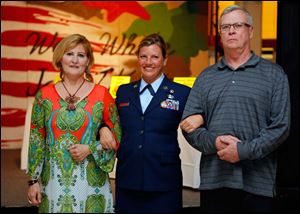 Teresa Fedor, left, and Jeff Lever, right, escort Air Force veteran Jen Bauer as she is announced at the Dancing with the Military Stars event.