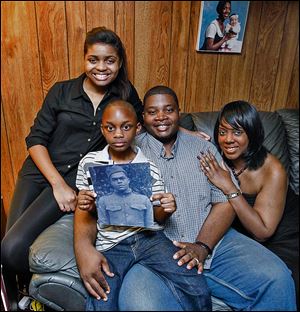 The Quinn family, from left Braniya, 15; Braylin, 7, and parents Anthony and Brandi, show a portrait of Homer Lee Quinn, Anthony's great uncle who died serving in the Army.