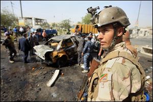 An Iraqi soldier stands guard at the scene of a bomb attack at Sadr City in Baghdad, Iraq, today.