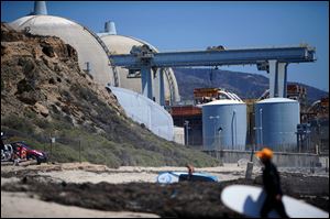 Surfers walk along a beach nearby the San Onofre Nuclear Power Plant in San Onofre, Calif. 