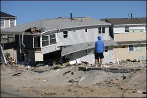 A man looks at damaged homes on  Fort Avenue in Ortley Beach, N.J., Sunday. While parts of New Jersey's shore has made great progress over the past seven months, towns still have a long way to go to recover from Superstorm Sandy. 