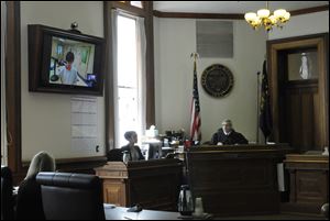 Grant Alan Acord, 17, upper left, is seen in a video feed from where he is being held on a television screen as Judge Matthew Donahue, right, speaks to lawyers today at the Benton County Courthouse in Corvallis, Ore.