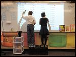  Kimari Barden, left, 7, and Nakeya Beberly, 7, work on their addition problems projected on a dry erase board in the classroom