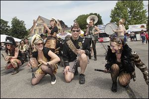 Crouching, from right, Taylor Kozak, Alex Pritchard, and Antha Ann, all of Detroit, swing and squat as they and other members of the Detroit Party Marching Band perform.