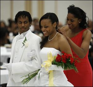 Chandler Johnson receives a pearl necklace from debutante-in-waiting Yatian Caldwell as her escort Caleb Willhight looks on.