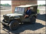  Vittorio Argento sits in an original Willys MB (Jeep) that he brought from Italy to the Willys-Overland factory site in Toledo. The vehicle was built on the site in 1943.  One of the original smokestacks from the factory still stands on the site.