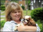  Liz Dickens holds her English toy spaniel, Winston, 7, at her home in Toledo. Winston suffered from frequent dislocations of his kneecaps, a common defect of smaller-breed dogs. One kneecap was fixed. Because the other kneecap defect is not as severe, Ms. Dickens is saving money for the second surgery.