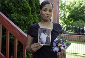 Breast cancer survivor Alicia Cook holds photos of family members who have also been afflicted by breast cancer, outside her home in Chicago. 