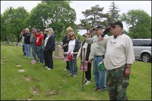 Izzy Ortiz, right, and the other volunteers salute after saying the name of a dead comrade in a brief ceremony the volunteers hold after placing about 500 flags in Lot 25.  A group of veterans placed U.S. flags on the graves of other veterans at Toledo Memorial Park in Sylvania on May 23, 2013.