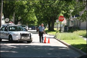 A Toledo Police Officer marks shell casings with cones at the corner of Moore and Elm streets in North Toledo.