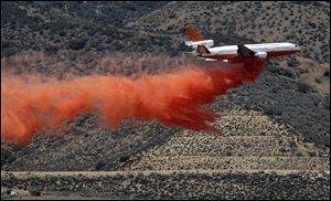 A DC-10 aerial tanker drops a line of fire retardant along the foothills of the Angeles National Forest where it becomes the Antelope Valley in an attempt to stop the Power Station fire if it comes that far, in Lancaster, Calif., Sunday.